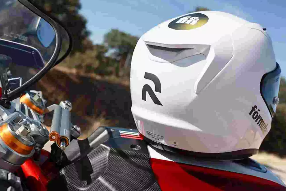 Persona con casco blanco de motociclista sentada sobre una moto roja en un entorno al aire libre Persona con casco blanco de motociclista sentada sobre una moto roja en un entorno al aire libre