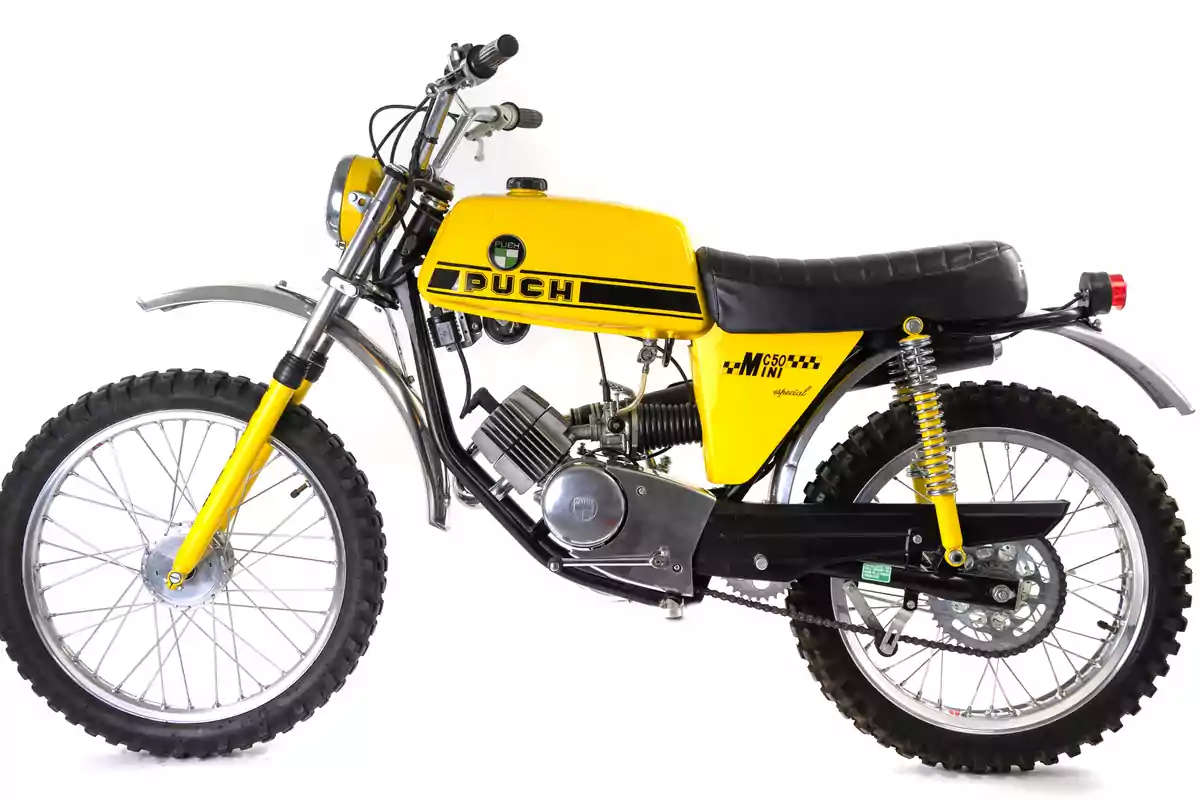 Motocicleta clásica Puch MC 50 Mini de color amarillo con detalles en negro y llantas de tacos sobre fondo blanco Motocicleta clásica Puch MC 50 Mini de color amarillo con detalles en negro y llantas de tacos sobre fondo blanco