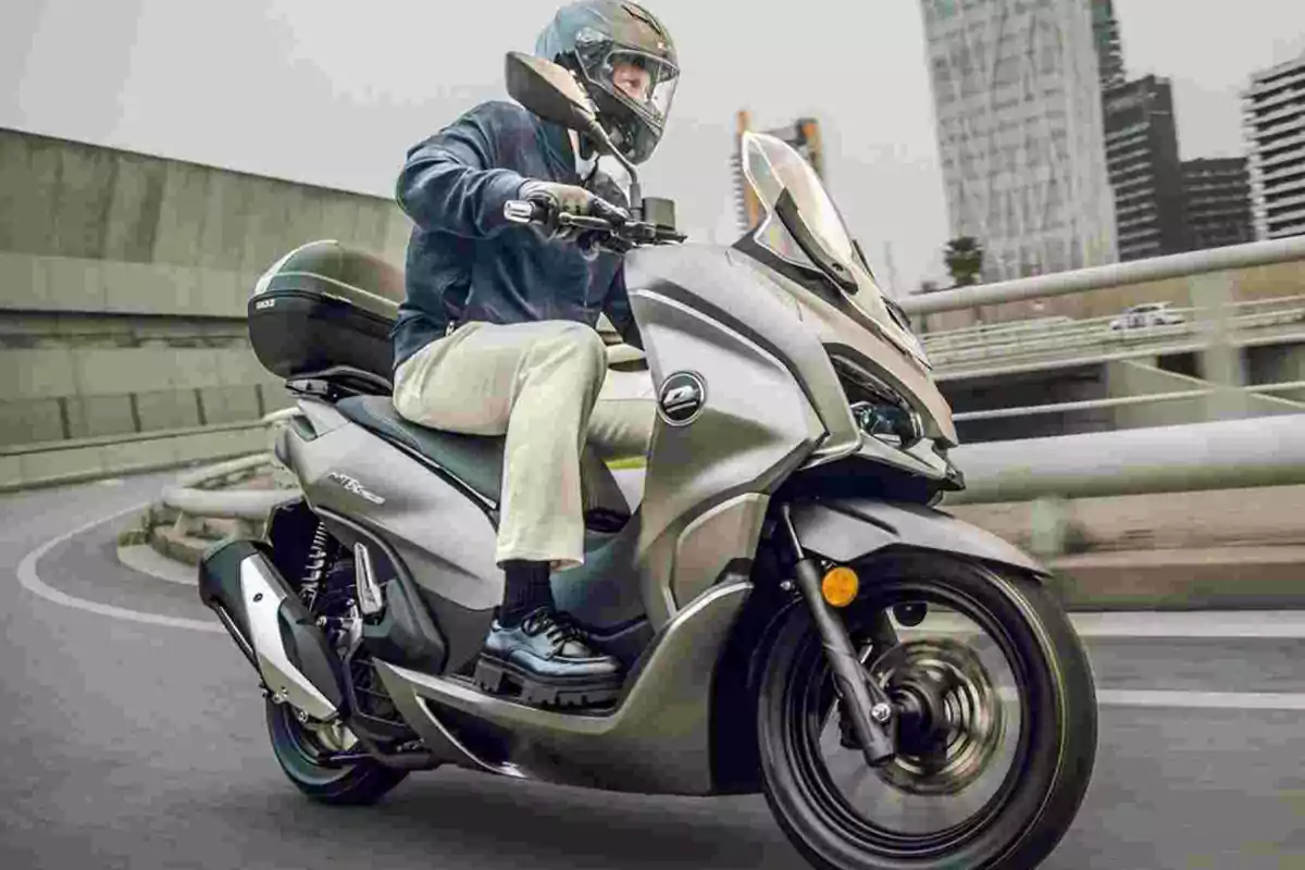 Persona conduciendo una motocicleta tipo scooter en una ciudad Persona conduciendo una motocicleta tipo scooter en una ciudad