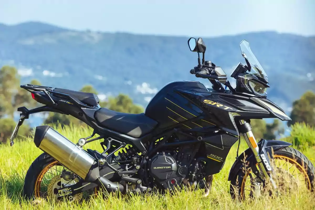Motocicleta negra modelo SRT 900 estacionada sobre césped con un paisaje de montañas al fondo Motocicleta negra modelo SRT 900 estacionada sobre césped con un paisaje de montañas al fondo