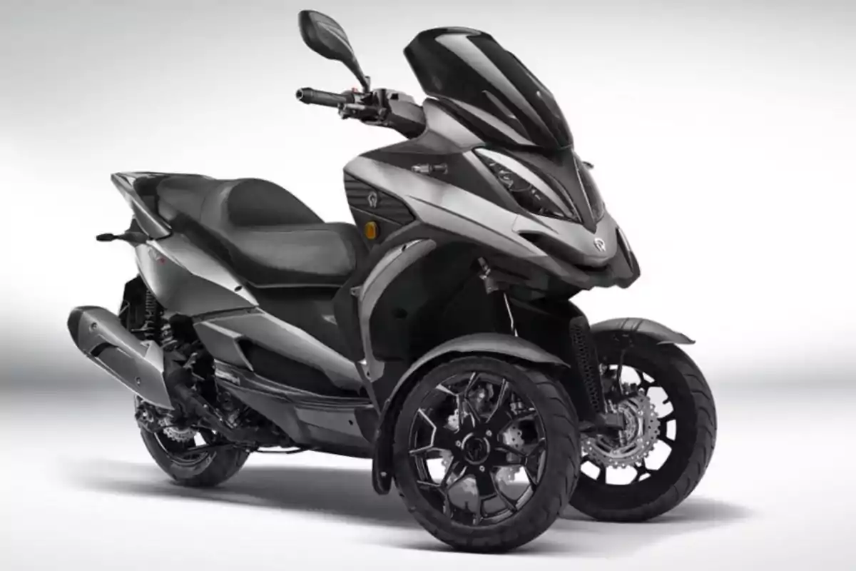 Motocicleta de tres ruedas color gris con diseño moderno y deportivo sobre fondo blanco