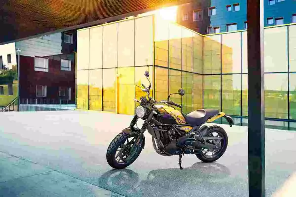 Motocicleta amarilla estacionada frente a un edificio moderno con paredes de vidrio y reflejos del sol al atardecer Motocicleta amarilla estacionada frente a un edificio moderno con paredes de vidrio y reflejos del sol al atardecer