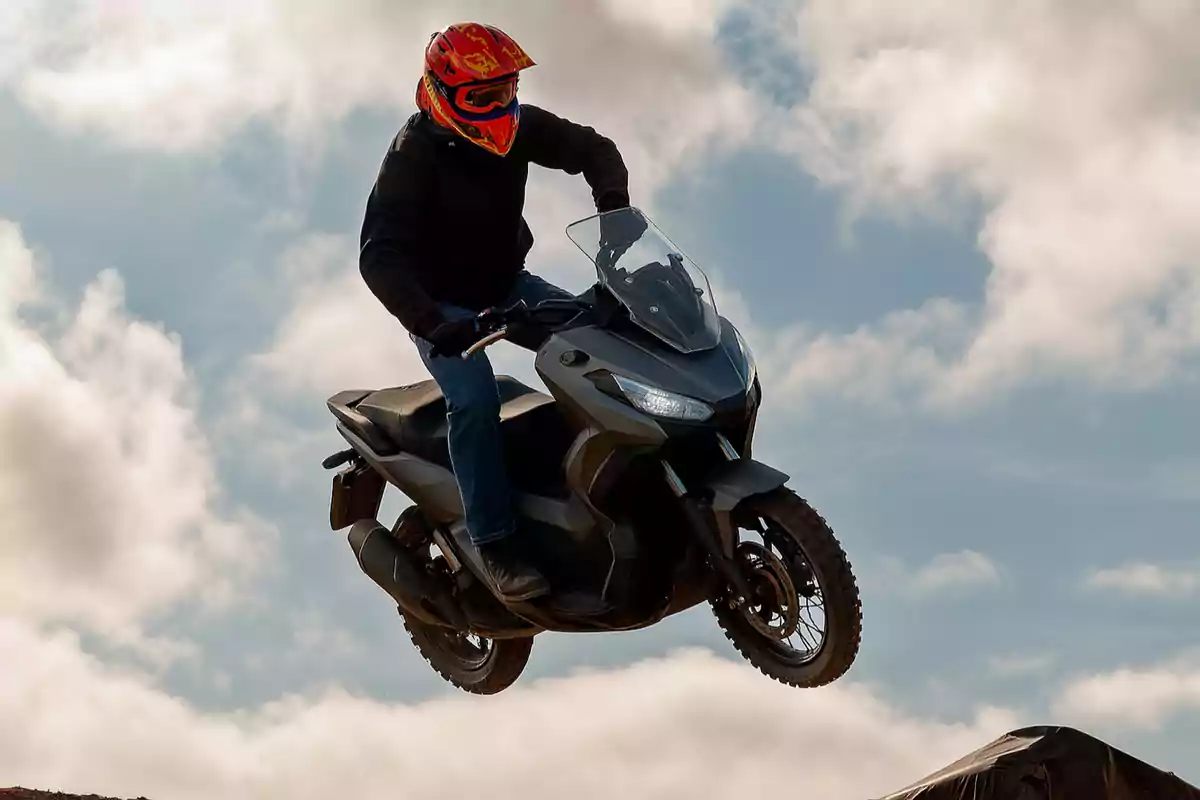 Persona con casco rojo realizando un salto en motocicleta sobre un fondo de cielo con nubes Persona con casco rojo realizando un salto en motocicleta sobre un fondo de cielo con nubes