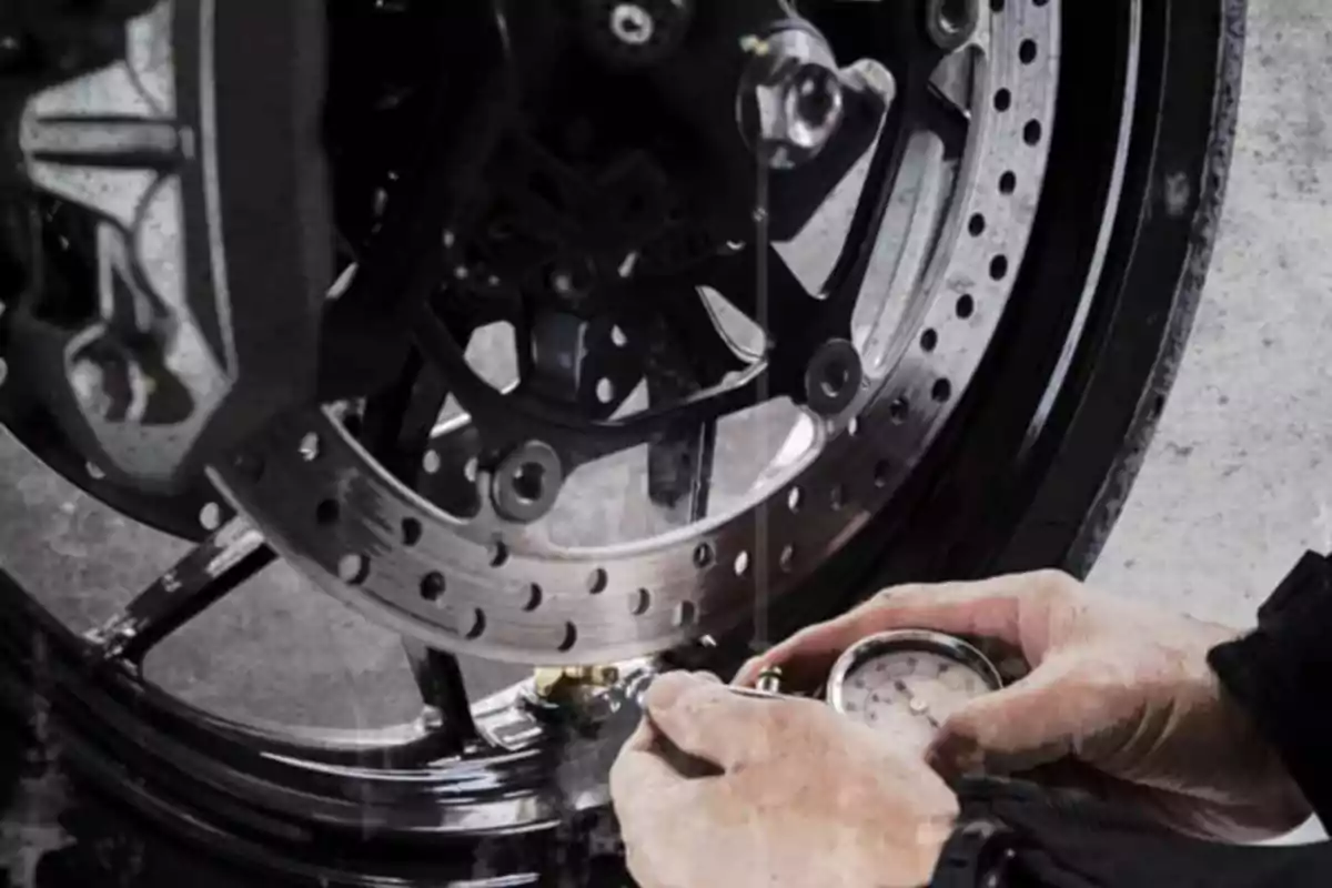 Person checking the front tire pressure of a motorcycle with a pressure gauge Person checking the front tire pressure of a motorcycle with a pressure gauge