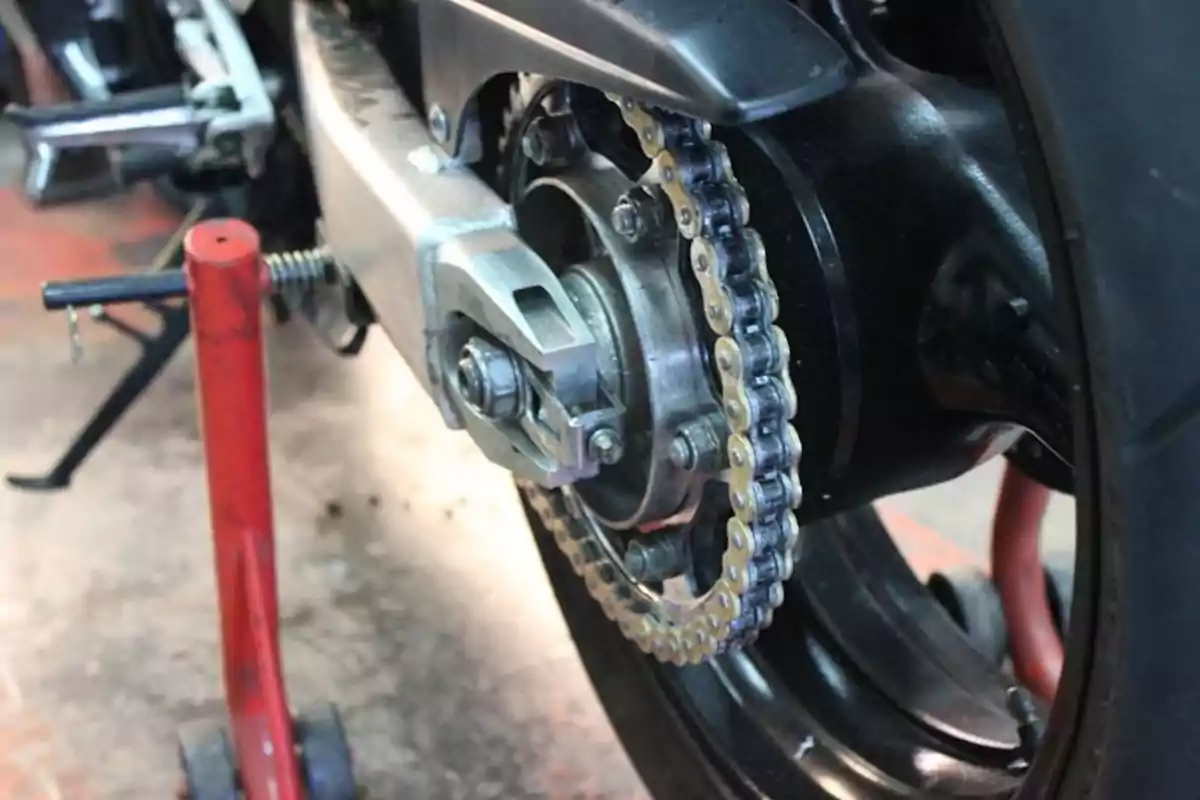 Cadena i roda del darrere d’una motocicleta sobre un suport vermell en un taller