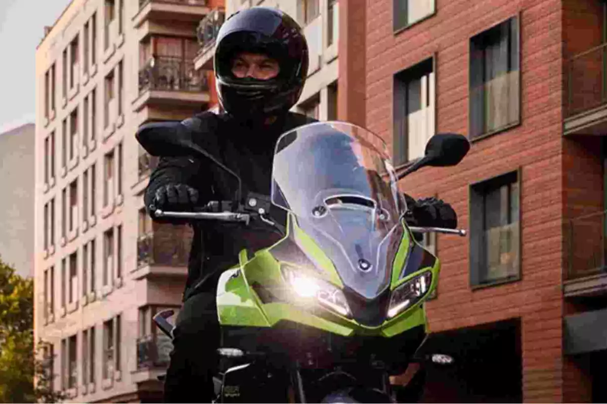Persona con casco negro conduciendo una motocicleta verde en una calle rodeada de edificios modernos Persona con casco negro conduciendo una motocicleta verde en una calle rodeada de edificios modernos