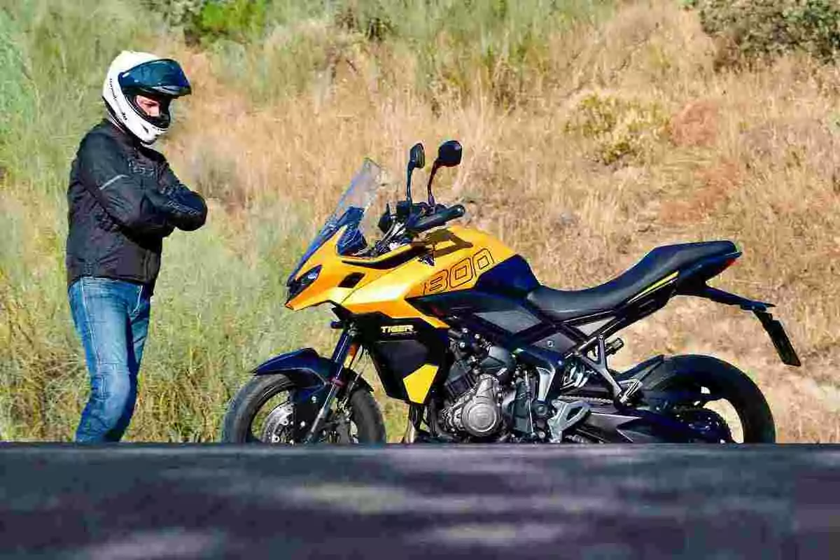 Persona con casco y chaqueta de motociclista de pie junto a una moto deportiva amarilla en un entorno natural Persona con casco y chaqueta de motociclista de pie junto a una moto deportiva amarilla en un entorno natural
