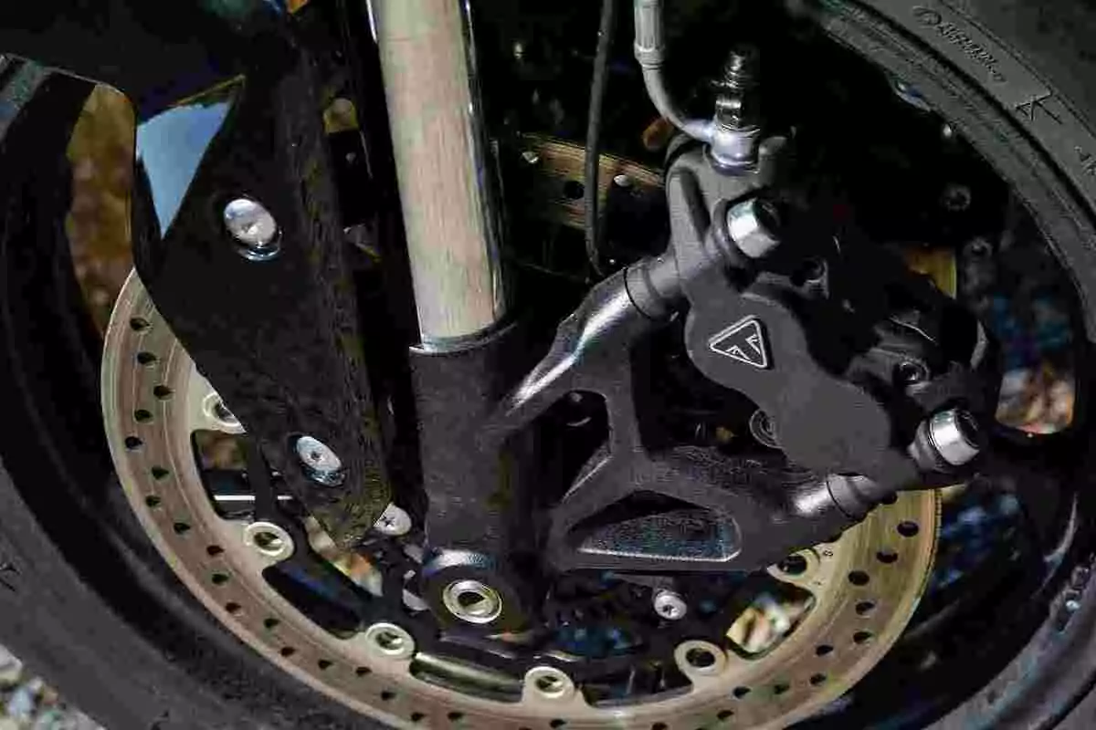 Detalle de un freno de disco delantero de motocicleta con pinza y suspensión visibles Detalle de un freno de disco delantero de motocicleta con pinza y suspensión visibles