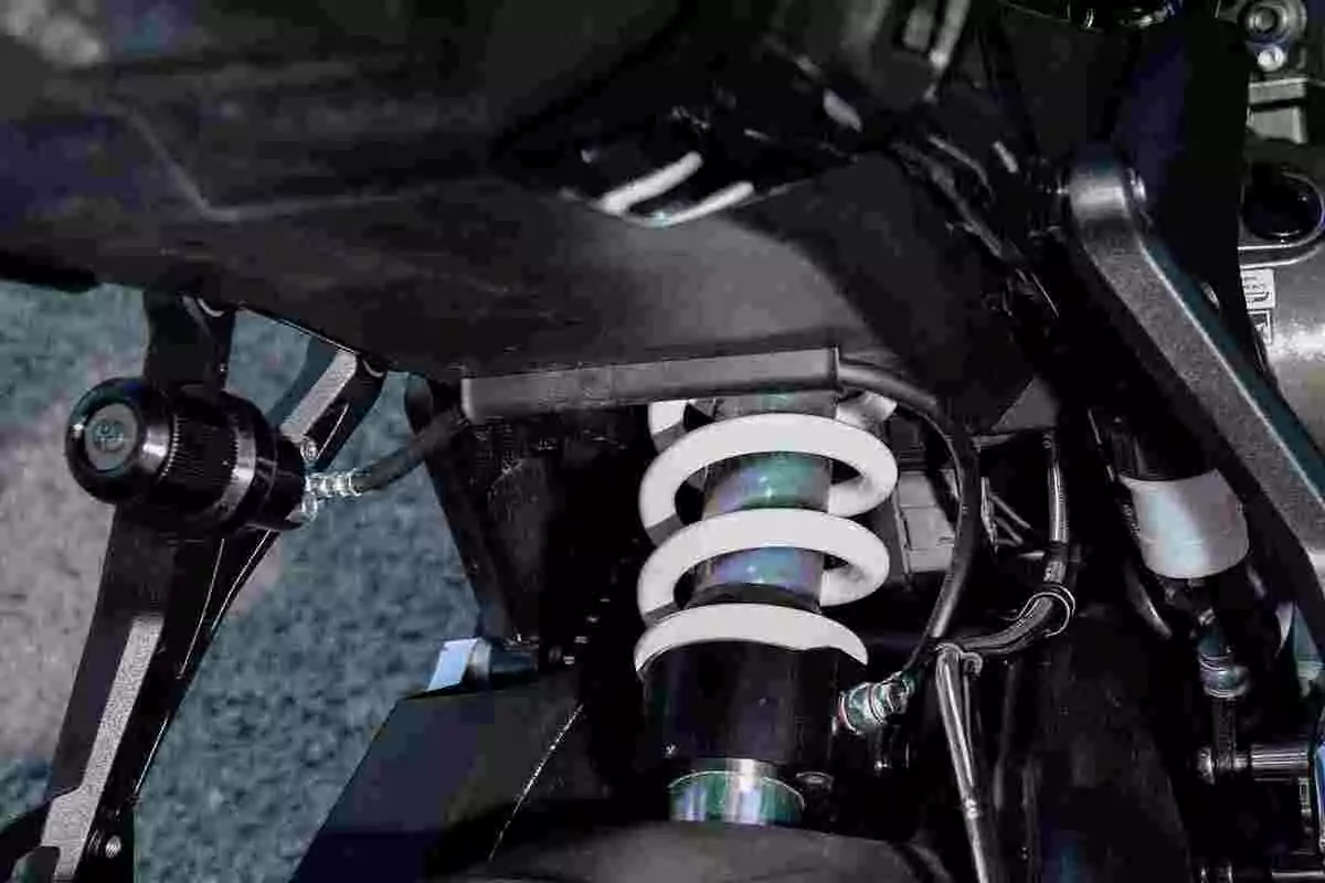 Amortiguador trasero de motocicleta con resorte blanco y componentes metálicos visibles Amortiguador trasero de motocicleta con resorte blanco y componentes metálicos visibles