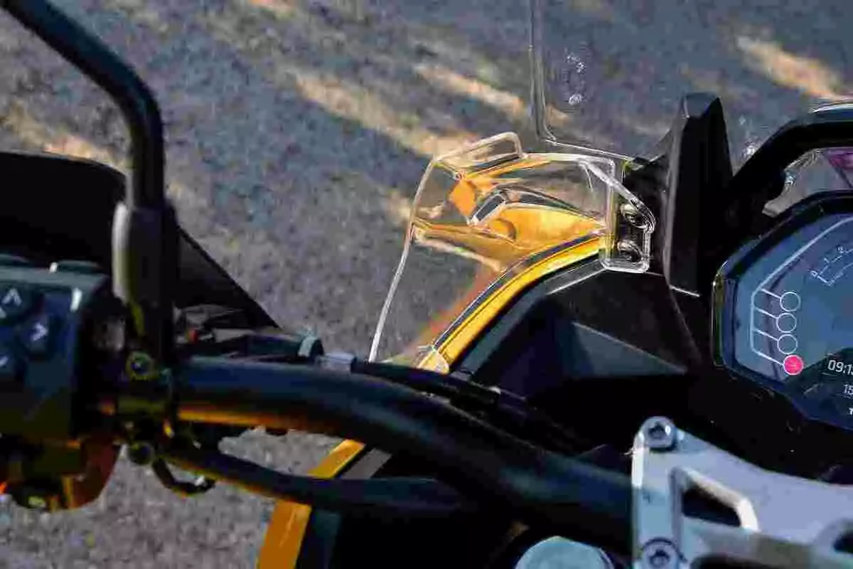Vista cercana del manillar y tablero digital de una motocicleta con parabrisas transparente y detalles en color amarillo Vista cercana del manillar y tablero digital de una motocicleta con parabrisas transparente y detalles en color amarillo