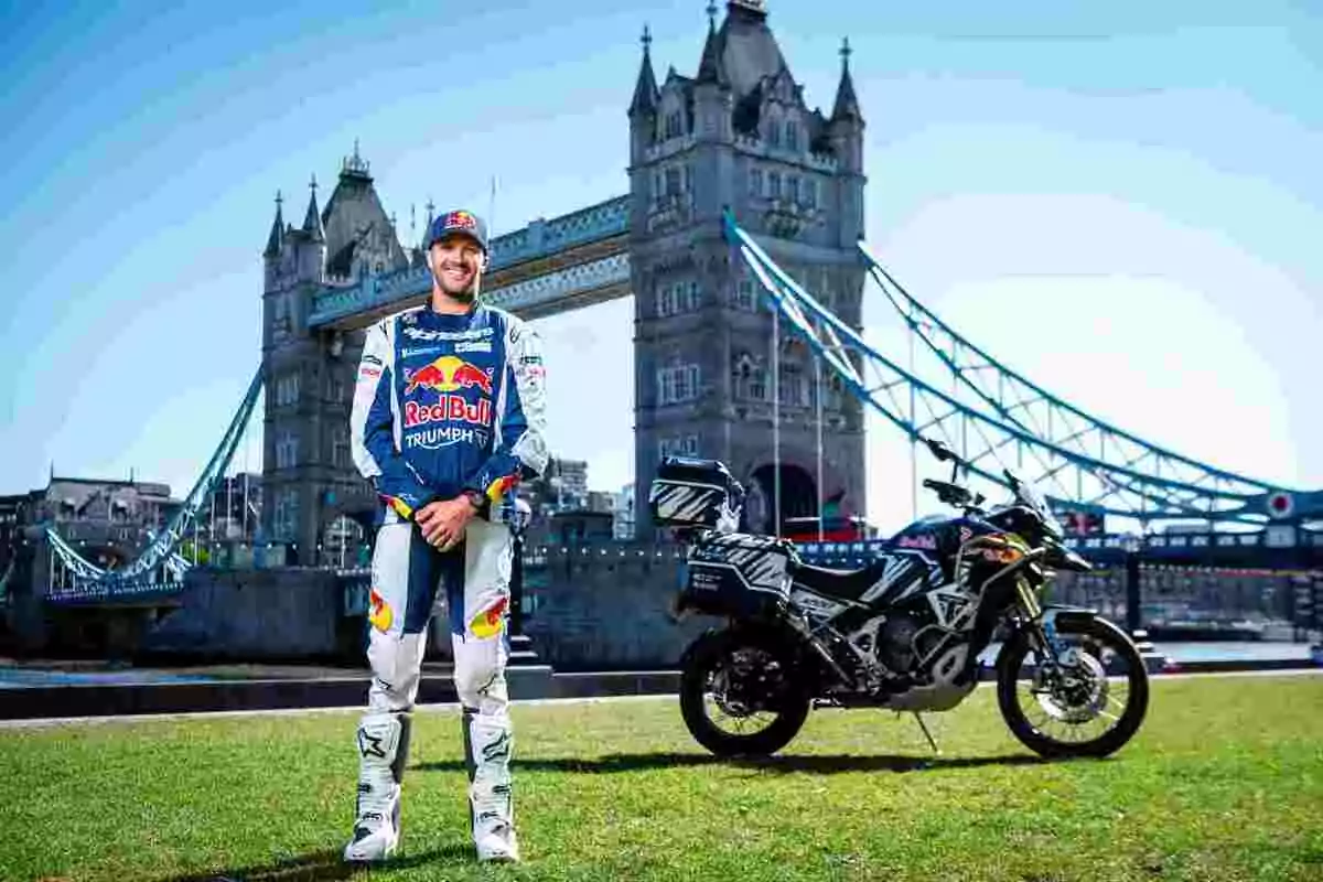 Piloto de motociclismo con uniforme de Red Bull posando junto a una motocicleta Triumph frente al Puente de la Torre en Londres Piloto de motociclismo con uniforme de Red Bull posando junto a una motocicleta Triumph frente al Puente de la Torre en Londres