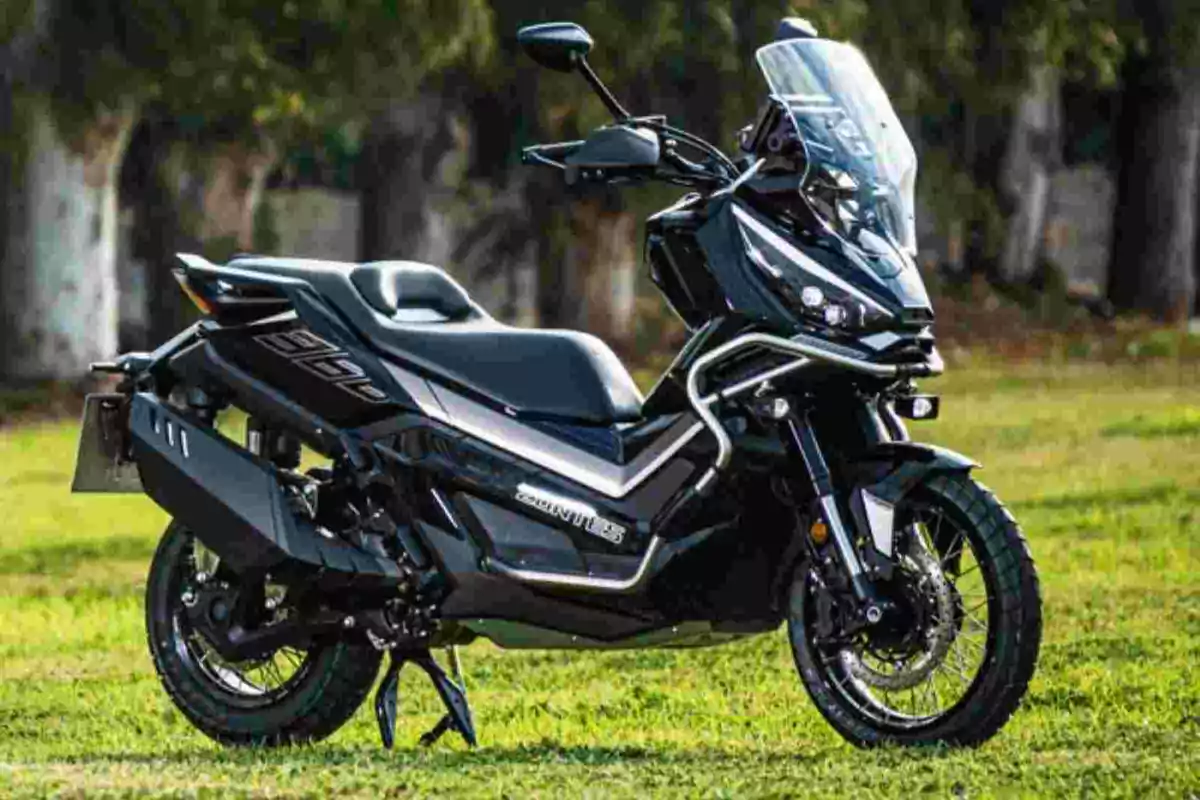 Motocicleta negra tipus scooter estacionada sobre gespa amb fons d’arbres desenfocats Motocicleta negra tipus scooter estacionada sobre gespa amb fons d’arbres desenfocats