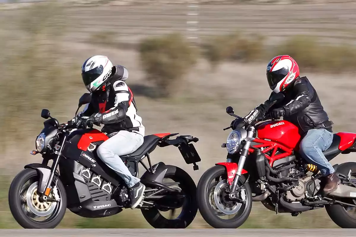 Dos personas con casco y chaqueta de protección montan motocicletas deportivas rojas en una carretera Dos personas con casco y chaqueta de protección montan motocicletas deportivas rojas en una carretera