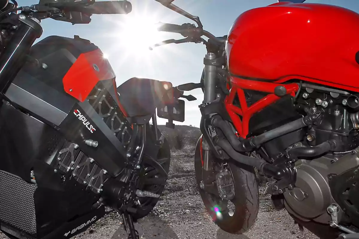 Two motorcycles parked side by side under the sunlight, one black with red details and the other red.
