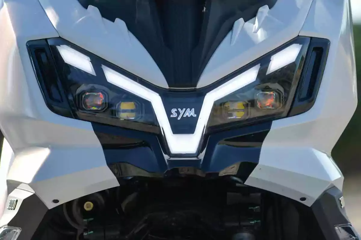 Frente de una motocicleta SYM con faros LED encendidos y diseño moderno Frente de una motocicleta SYM con faros LED encendidos y diseño moderno