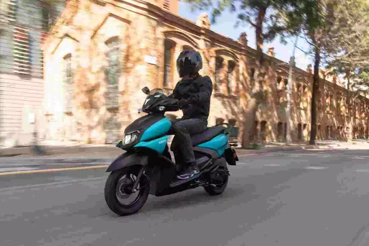 Persona conduciendo una moto azul por una calle urbana con edificios antiguos al fondo Persona conduciendo una moto azul por una calle urbana con edificios antiguos al fondo