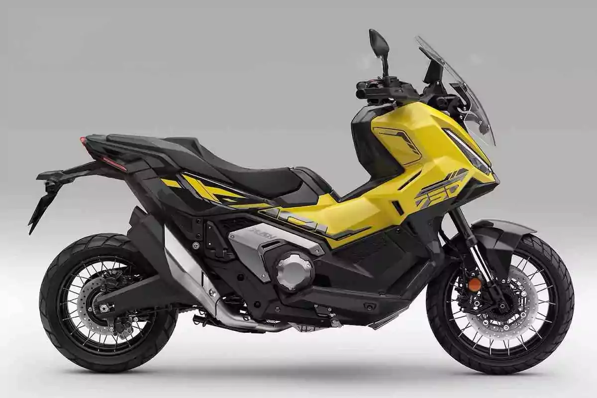 Motocicleta amarilla y negra de estilo aventurero con parabrisas y llantas de radios sobre fondo gris Motocicleta amarilla y negra de estilo aventurero con parabrisas y llantas de radios sobre fondo gris