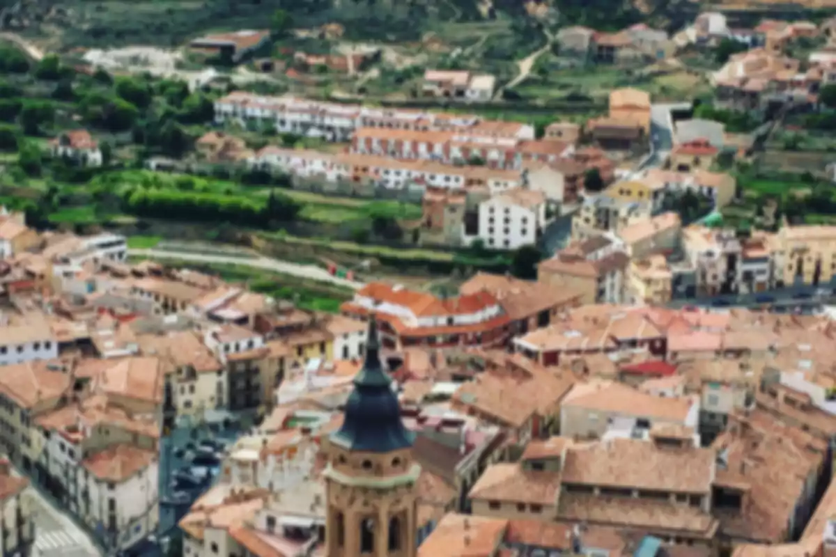 Vista aérea borrosa de un pueblo con tejados rojos y una iglesia destacada en primer plano Vista aérea borrosa de un pueblo con tejados rojos y una iglesia destacada en primer plano