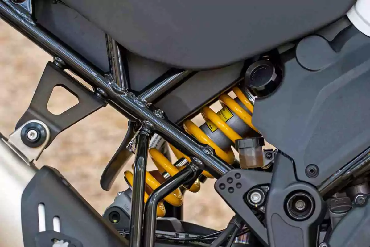 Detail of the rear shock absorber of a motorcycle with a yellow spring and black metal structure Detail of the rear shock absorber of a motorcycle with a yellow spring and black metal structure