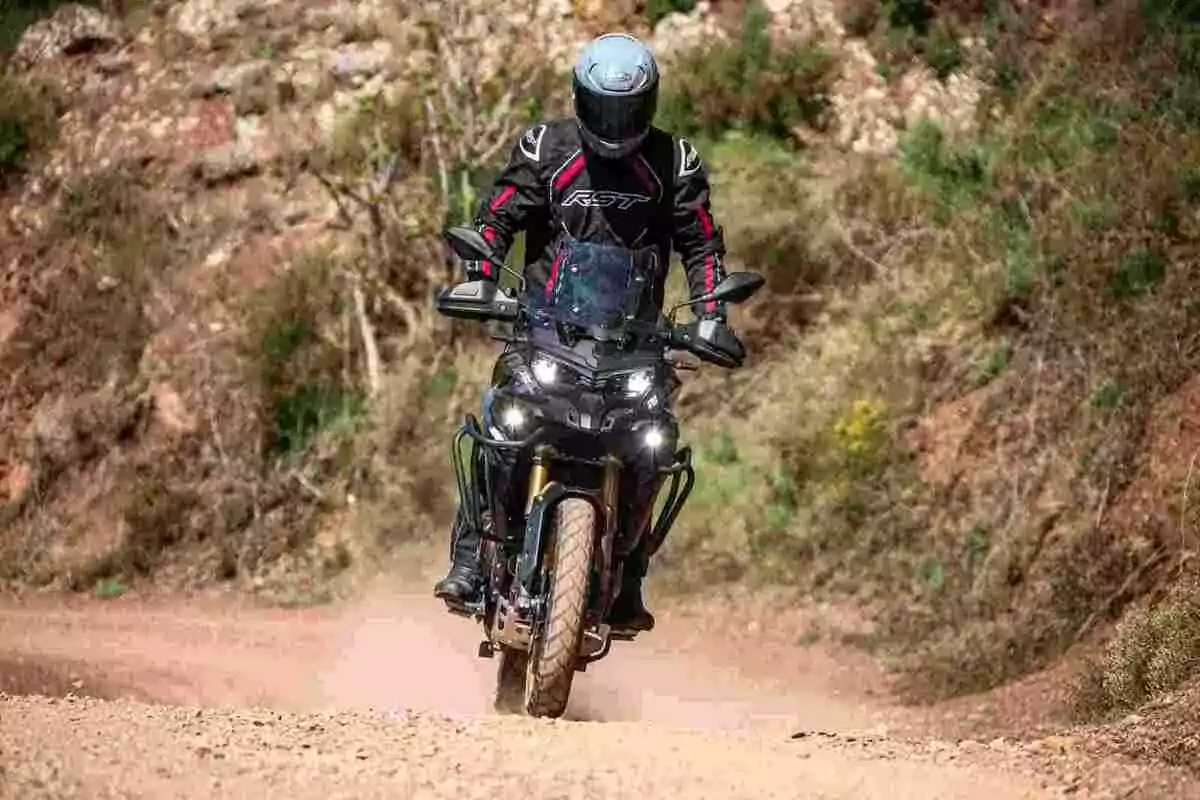 Person riding a motorcycle on a dirt road surrounded by vegetation and rocks Person riding a motorcycle on a dirt road surrounded by vegetation and rocks