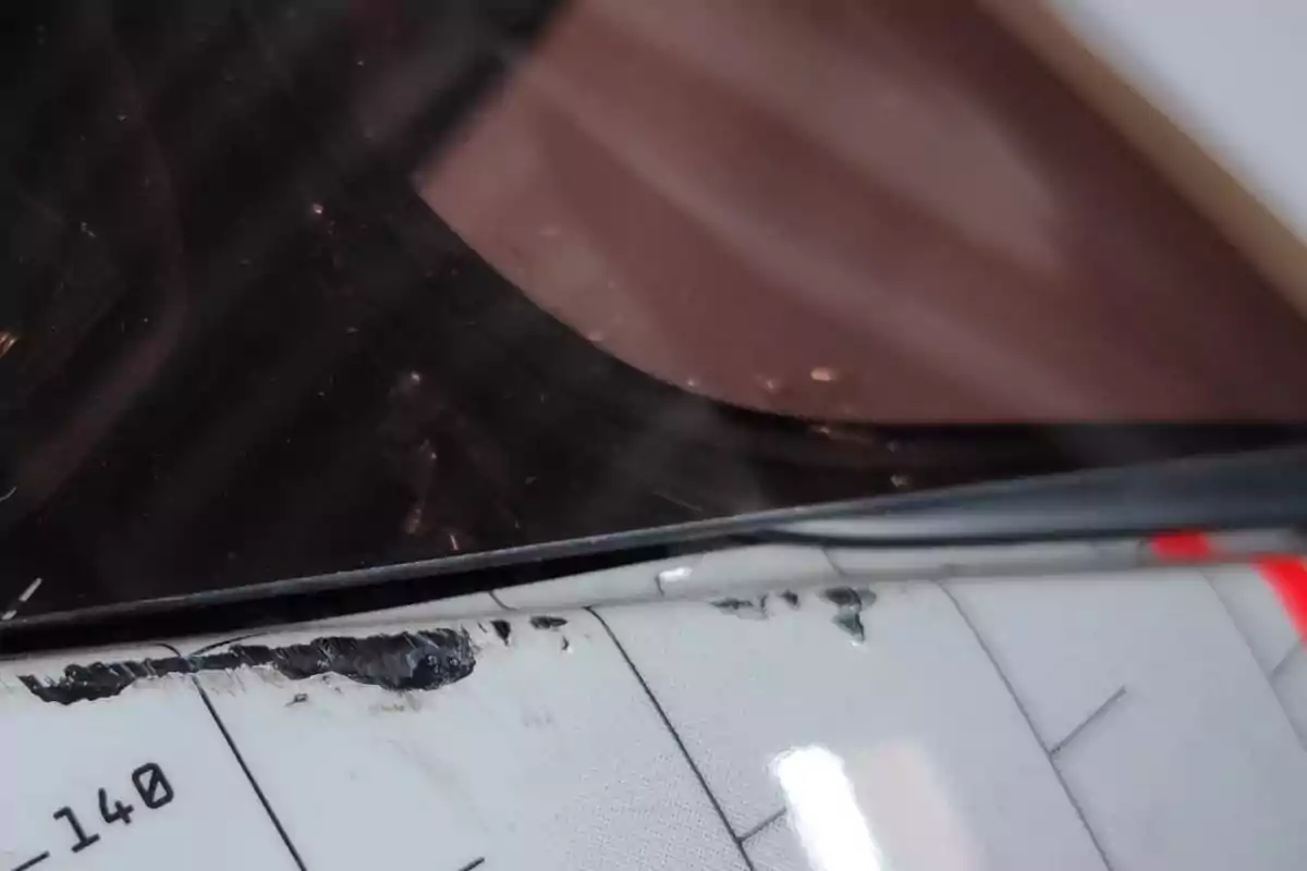 Detalle de un parabrisas con marcas negras y una superficie blanca con líneas y números Detalle de un parabrisas con marcas negras y una superficie blanca con líneas y números