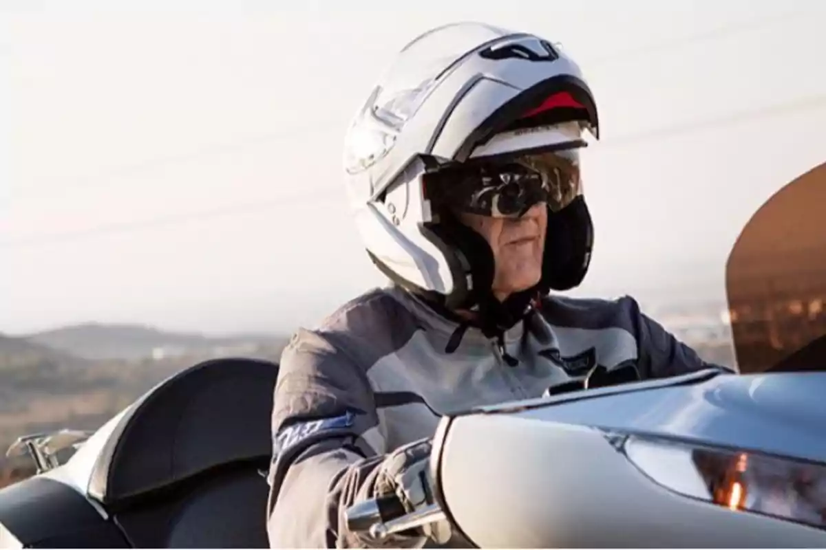 Persona gran conduint una motocicleta amb casc i ulleres de sol en un entorn a l’aire lliure Persona gran conduint una motocicleta amb casc i ulleres de sol en un entorn a l’aire lliure