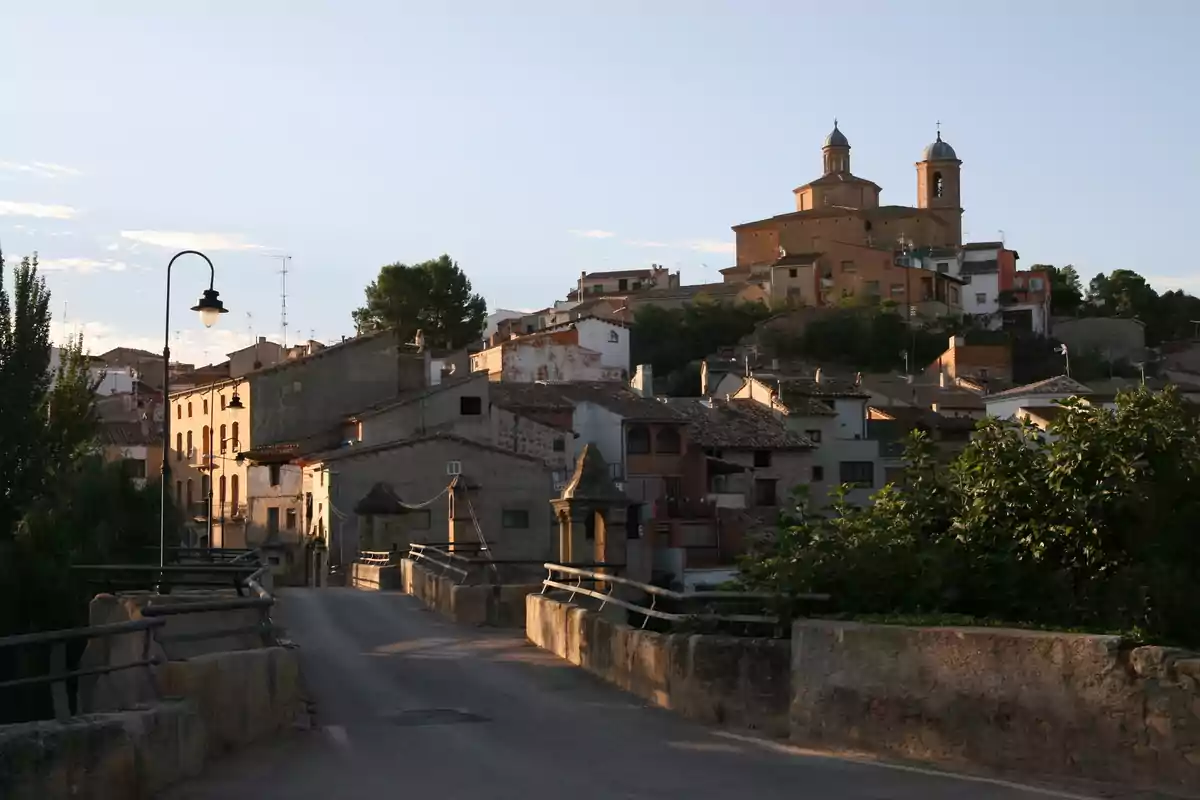 Vista de un pueblo con casas de tejados inclinados y una iglesia en lo alto de una colina al atardecer Vista de un pueblo con casas de tejados inclinados y una iglesia en lo alto de una colina al atardecer