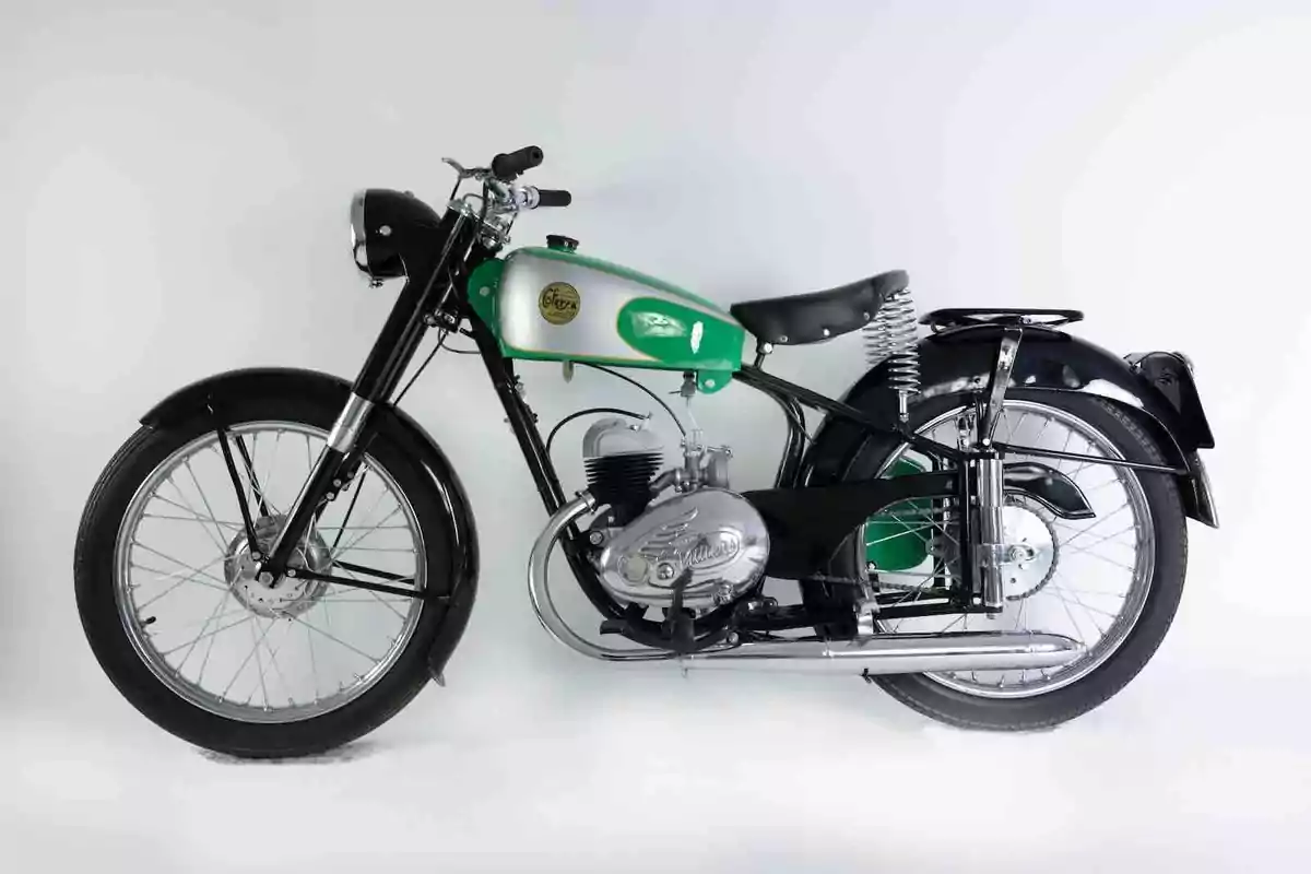 Motocicleta clásica de color verde y negro con detalles cromados sobre un fondo blanco Motocicleta clásica de color verde y negro con detalles cromados sobre un fondo blanco