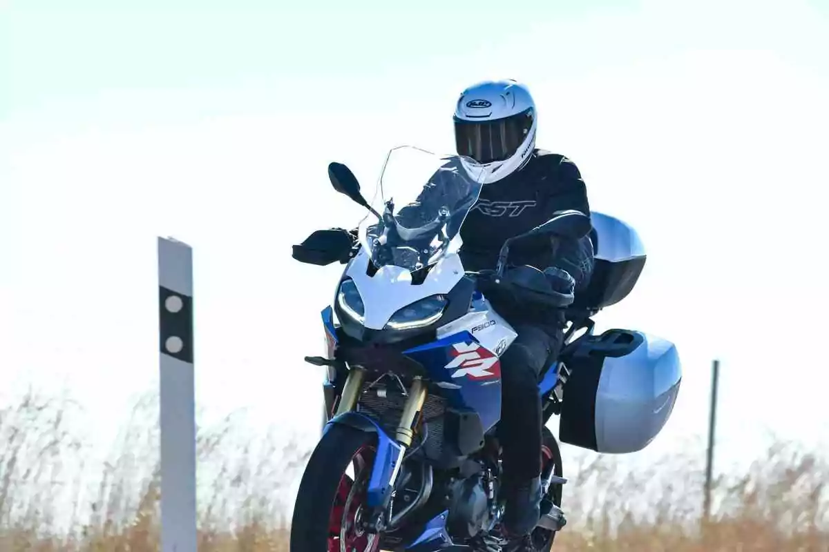 Person riding a blue sport motorcycle with side bags on a rural road Person riding a blue sport motorcycle with side bags on a rural road