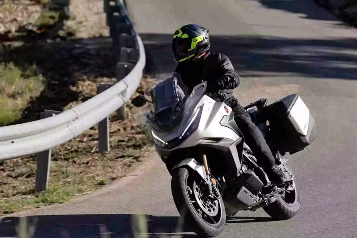 Person riding a white motorcycle on a curved road with a metal guardrail Person riding a white motorcycle on a curved road with a metal guardrail