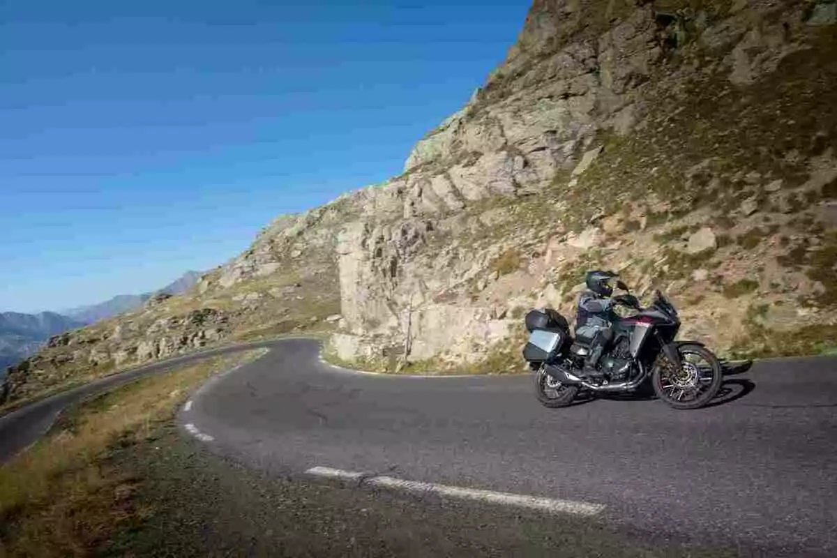 Motorcyclist riding on a mountain road with sharp curves and clear skies Motorcyclist riding on a mountain road with sharp curves and clear skies