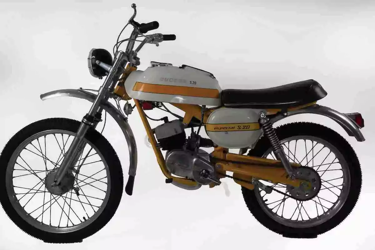 Motocicleta clásica de color blanco y amarillo con asiento negro y detalles cromados sobre un fondo blanco Motocicleta clásica de color blanco y amarillo con asiento negro y detalles cromados sobre un fondo blanco