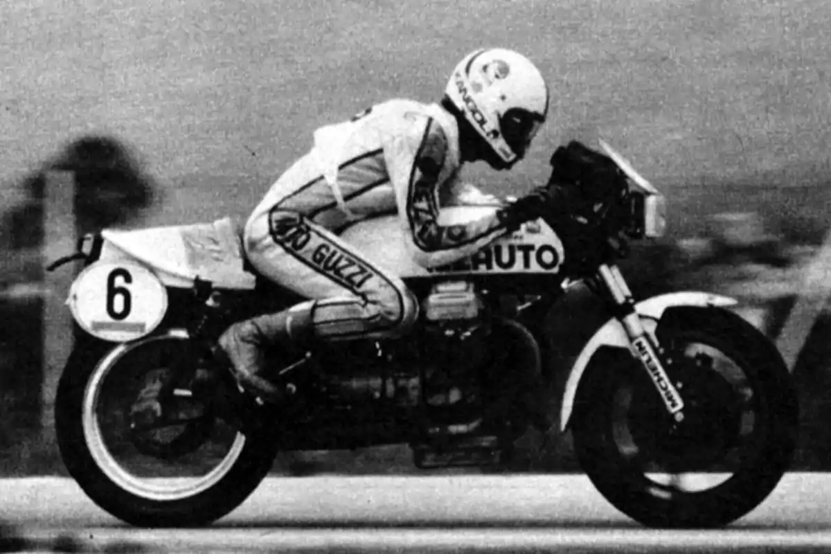 Piloto de motociclismo compitiendo en una carrera sobre una moto Moto Guzzi con el número 6 en la llanta delantera, usando un traje y casco de protección Piloto de motociclismo compitiendo en una carrera sobre una moto Moto Guzzi con el número 6 en la llanta delantera, usando un traje y casco de protección