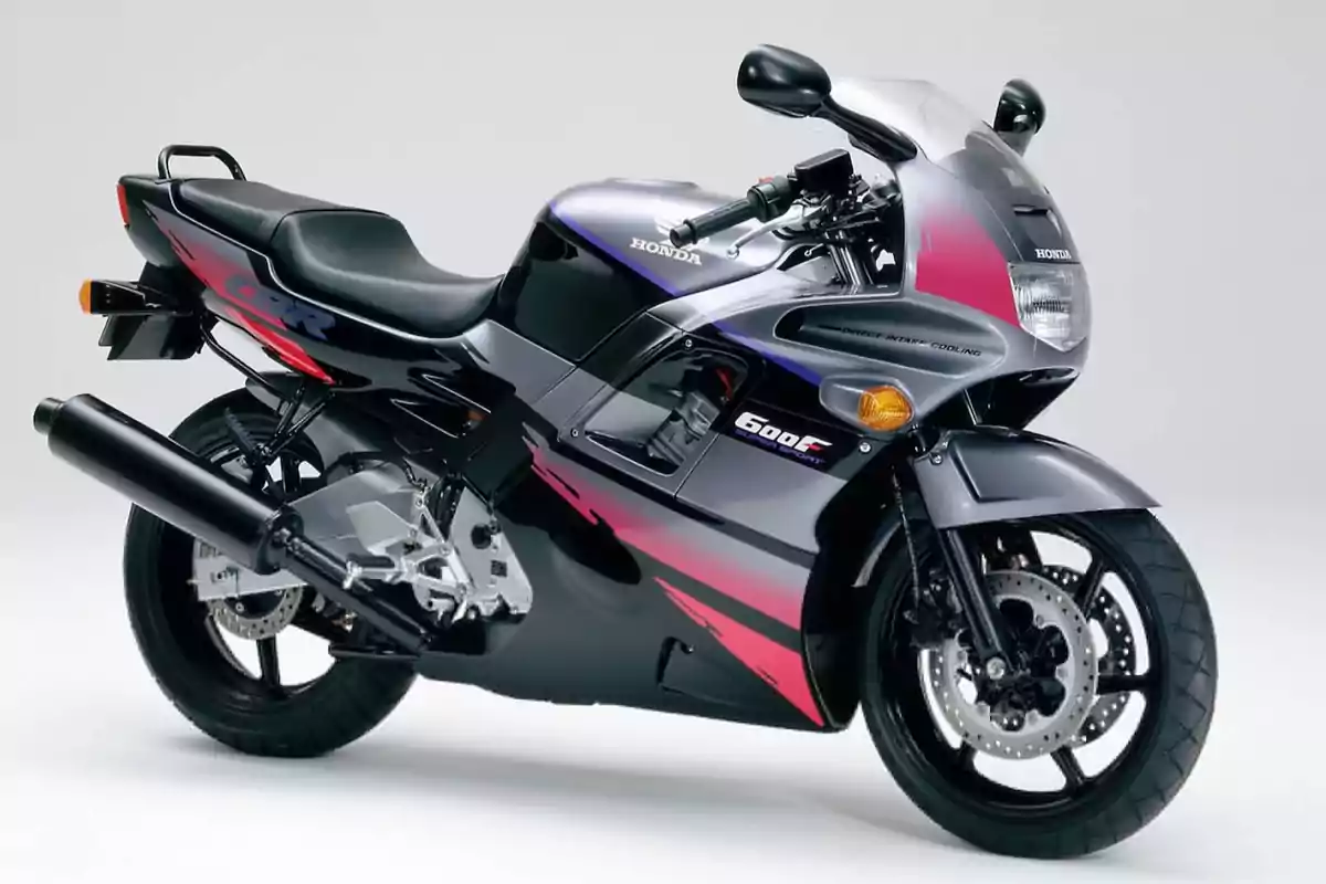 Motocicleta deportiva Honda CBR 600F de color negro con detalles en rosa y morado sobre un fondo blanco Motocicleta deportiva Honda CBR 600F de color negro con detalles en rosa y morado sobre un fondo blanco