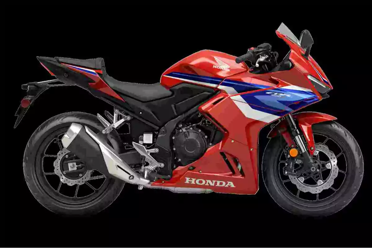 Motocicleta deportiva Honda de color rojo con detalles en azul y blanco sobre fondo negro Motocicleta deportiva Honda de color rojo con detalles en azul y blanco sobre fondo negro