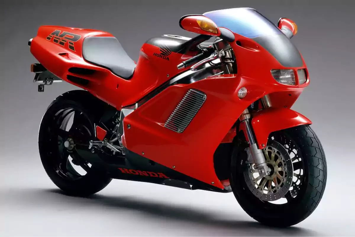 Motocicleta deportiva Honda de color rojo con carenado aerodinámico y detalles en negro sobre un fondo gris neutro Motocicleta deportiva Honda de color rojo con carenado aerodinámico y detalles en negro sobre un fondo gris neutro