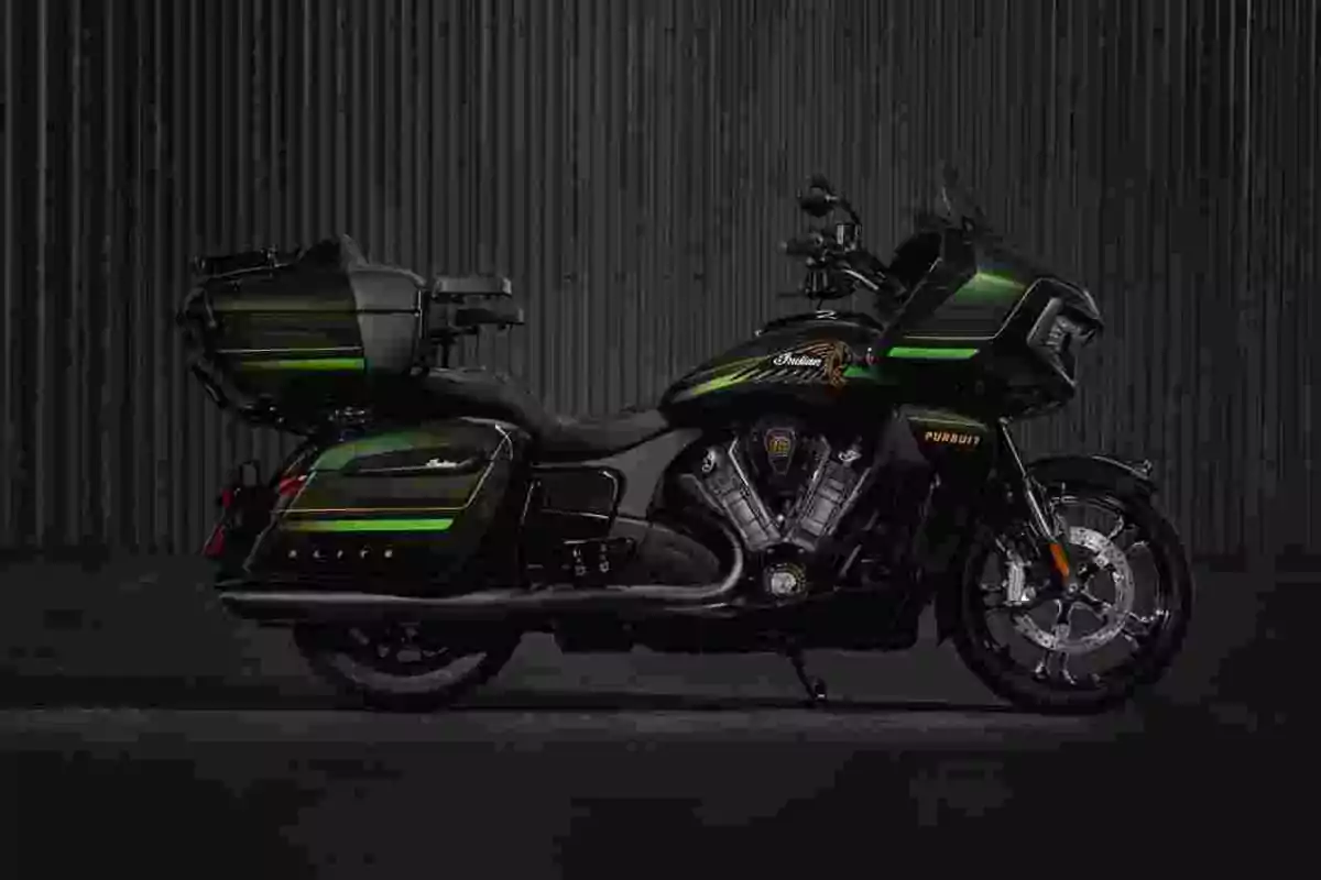 Motocicleta touring negra amb detalls verds i grocs estacionada davant d’un fons fosc de línies verticals Motocicleta touring negra amb detalls verds i grocs estacionada davant d’un fons fosc de línies verticals