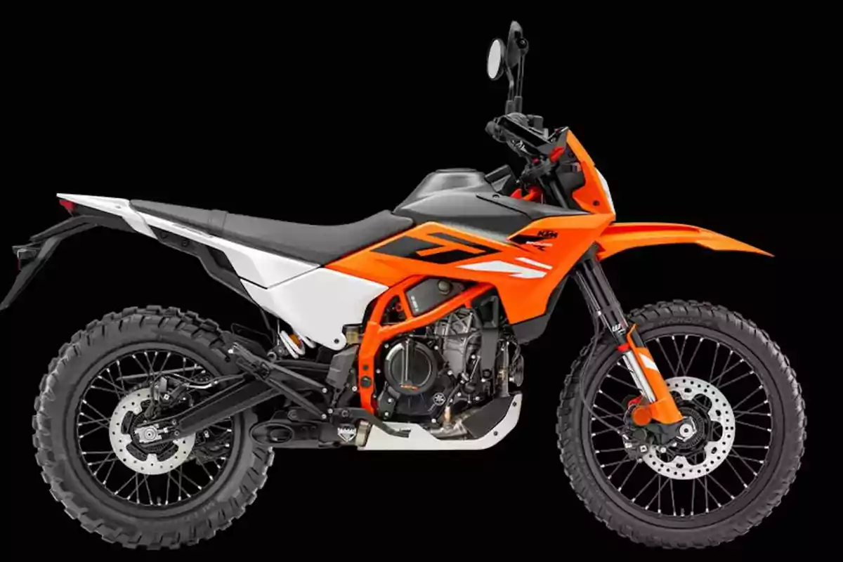 Motocicleta tipus enduro de color taronja, blanc i negre sobre fons negre Motocicleta tipus enduro de color taronja, blanc i negre sobre fons negre