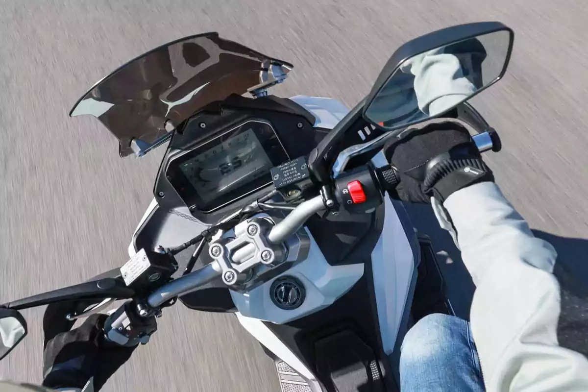 Persona conduciendo una motocicleta vista desde arriba mostrando el manillar, el tablero digital y los espejos retrovisores Persona conduciendo una motocicleta vista desde arriba mostrando el manillar, el tablero digital y los espejos retrovisores