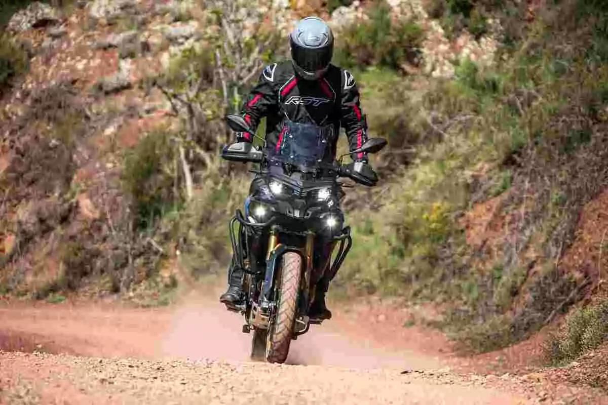 Persona conduciendo una motocicleta por un camino de tierra rodeado de vegetación Persona conduciendo una motocicleta por un camino de tierra rodeado de vegetación
