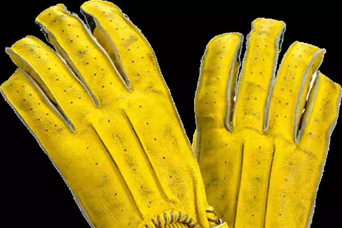 Un par de guantes amarillos de cuero con pequeños orificios de ventilación sobre un fondo negro Un par de guantes amarillos de cuero con pequeños orificios de ventilación sobre un fondo negro