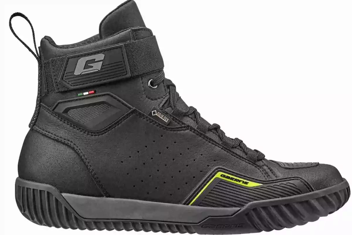 Bota negra de motociclista con detalles en amarillo y una pequeña bandera de Italia en el costado Bota negra de motociclista con detalles en amarillo y una pequeña bandera de Italia en el costado