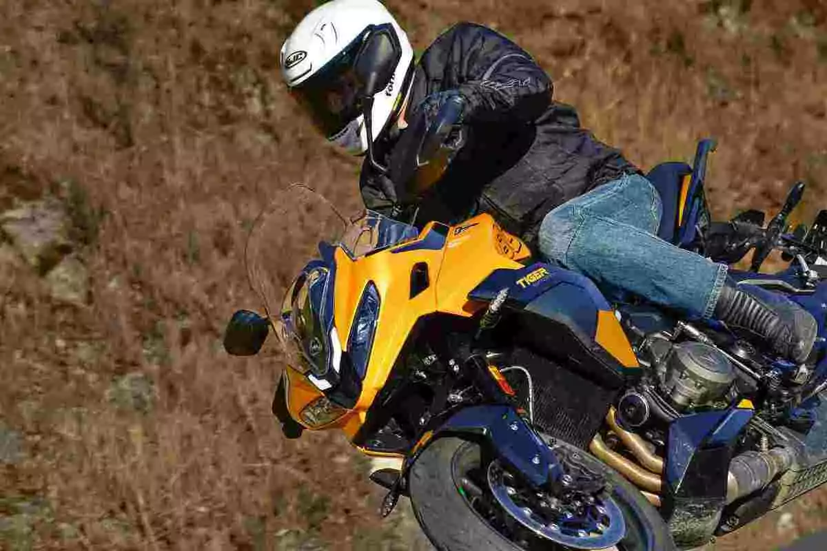 Persona amb casc blanc i jaqueta negra conduint una motocicleta esportiva groga en una corba Persona amb casc blanc i jaqueta negra conduint una motocicleta esportiva groga en una corba