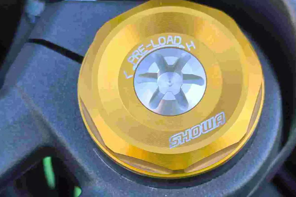 Detalle de un ajustador dorado de precarga de suspensión Showa en una motocicleta Detalle de un ajustador dorado de precarga de suspensión Showa en una motocicleta