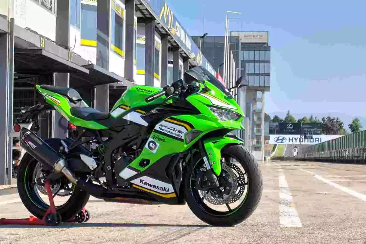 Motocicleta deportiva Kawasaki verde estacionada en un circuito de carreras junto a los boxes Motocicleta deportiva Kawasaki verde estacionada en un circuito de carreras junto a los boxes