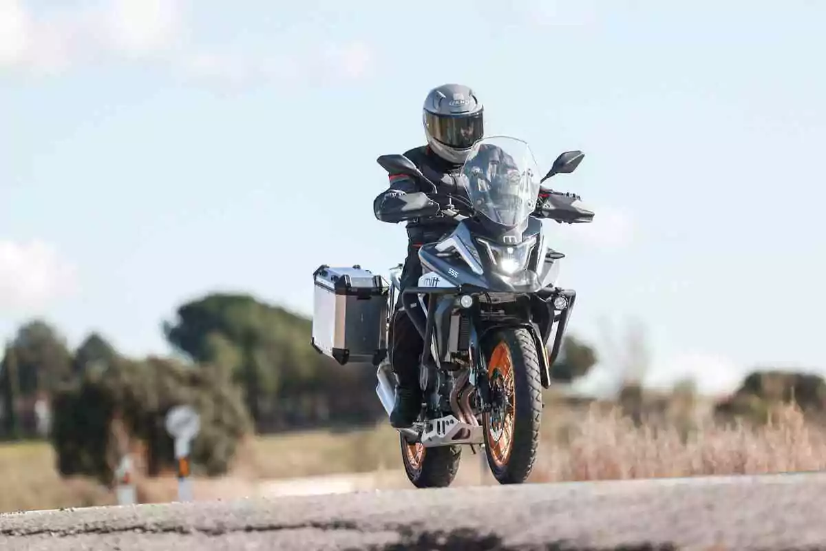 Persona conduciendo una motocicleta de aventura en una carretera con paisaje natural de fondo Persona conduciendo una motocicleta de aventura en una carretera con paisaje natural de fondo