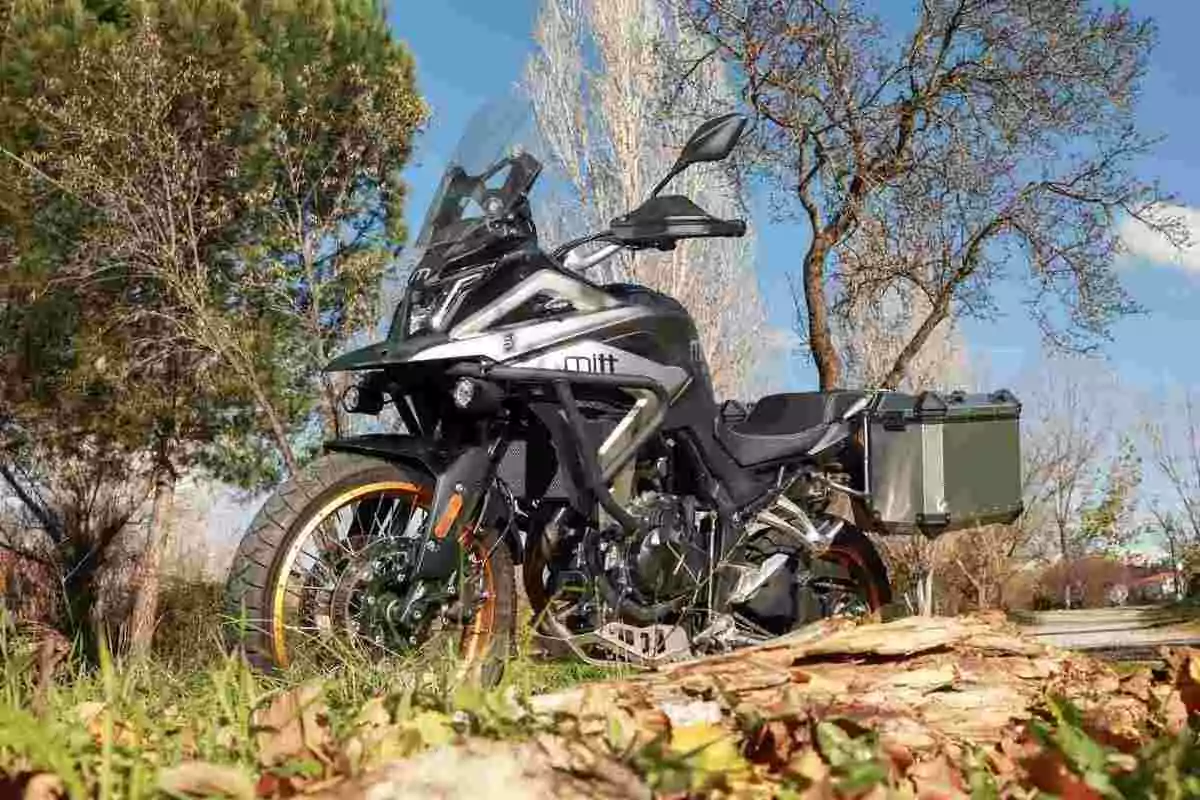 Motocicleta de aventura estacionada en un entorno natural con árboles y cielo azul de fondo Motocicleta de aventura estacionada en un entorno natural con árboles y cielo azul de fondo