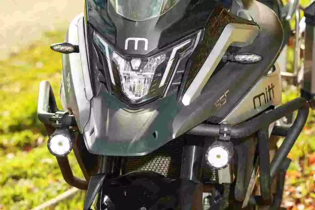 Frontal de una motocicleta Mitt con faros encendidos y detalles en color negro y gris. Frontal de una motocicleta Mitt con faros encendidos y detalles en color negro y gris.