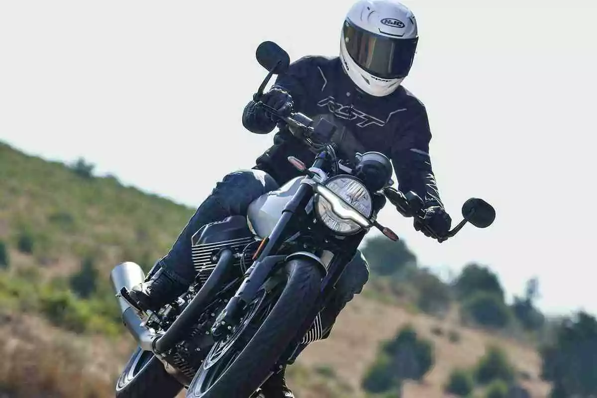 Persona conduciendo una motocicleta en una carretera al aire libre con paisaje natural de fondo