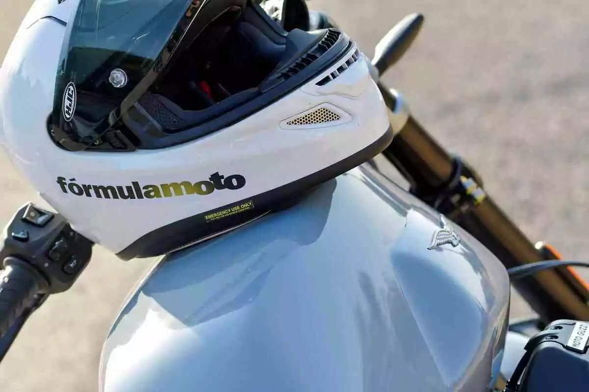 Casco blanco con visera negra apoyado sobre el tanque de una motocicleta Moto Guzzi Casco blanco con visera negra apoyado sobre el tanque de una motocicleta Moto Guzzi